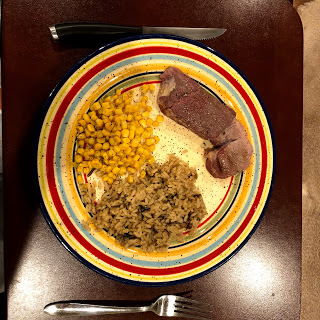 Venison steak with corn and wild rice on a colorful plate