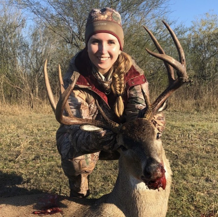 Jessica holding up large whitetail buck in the sunlight