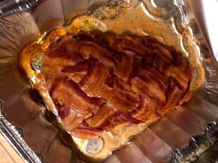 wild turkey breast covered in bacon in a silver tray for serving